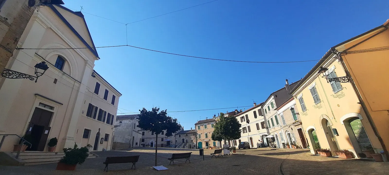 Centro storico di Camerata Picena con piazza principale chiesa e palazzi storici sotto cielo azzurro