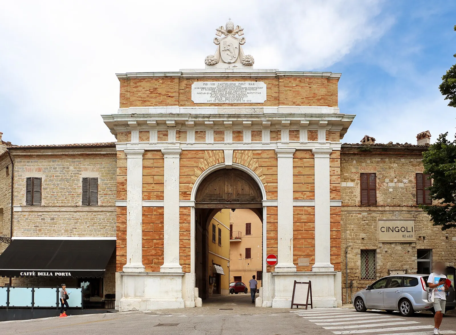 Porta monumentale con stemma e lapide in mattoni bianchi e rossi nel centro storico di Cingoli nelle Marche