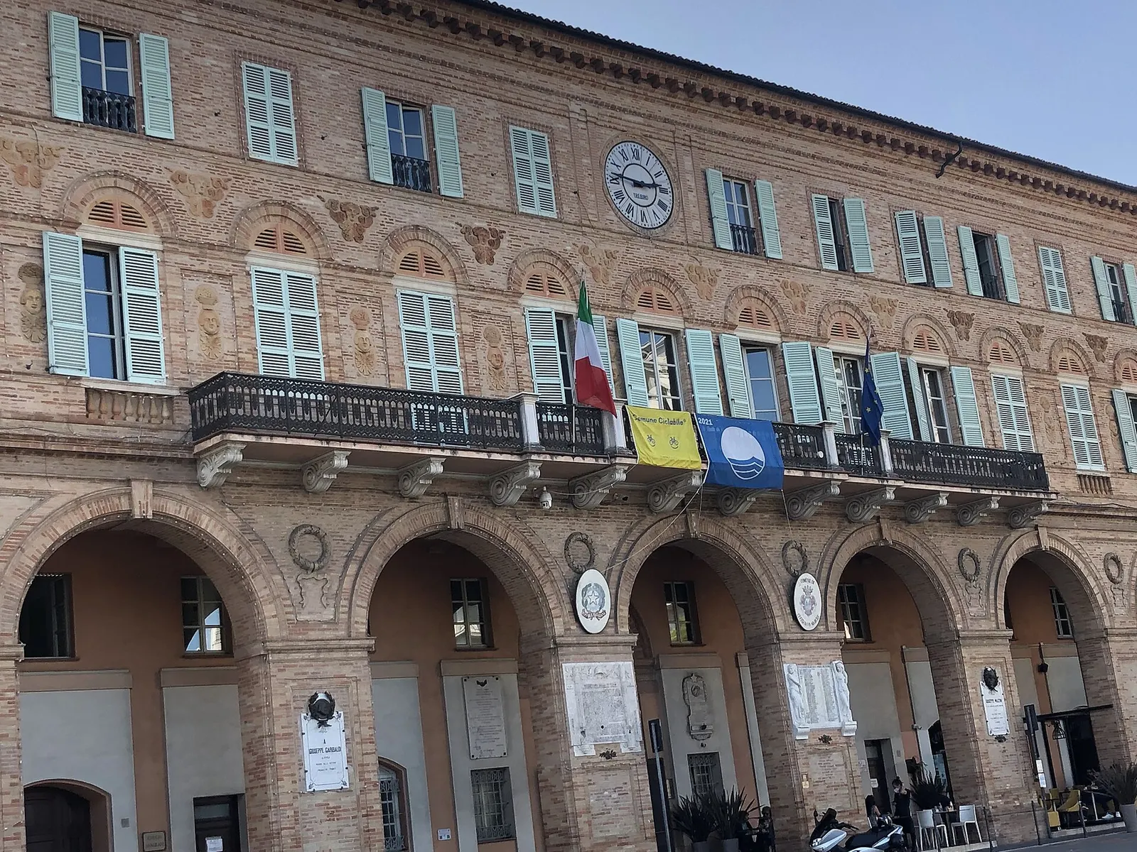Palazzo storico in mattoni con portici e bandiere a Civitanova Marche durante il festival Popsophia