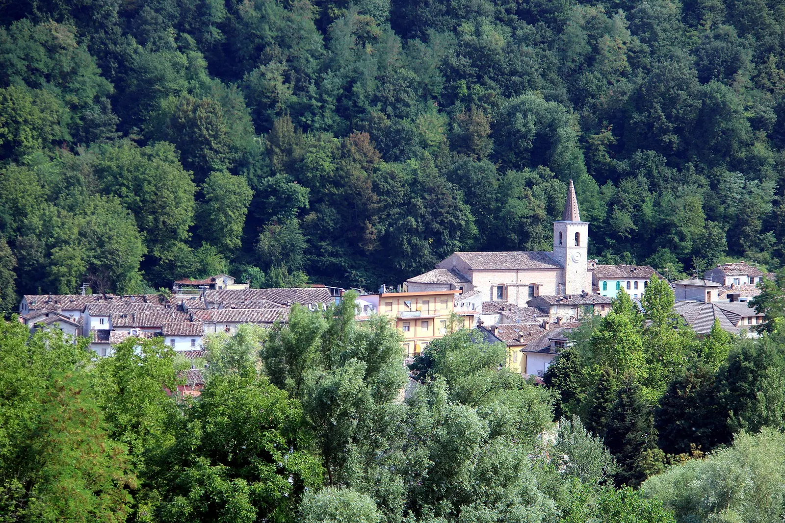 Veduta panoramica di Comunanza con il campanile della chiesa tra le abitazioni e i boschi dei Monti Sibillini