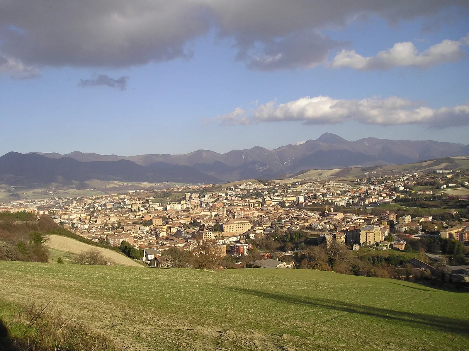 Panorama di Fabriano con centro storico e Appennino marchigiano sullo sfondo sotto un cielo nuvoloso