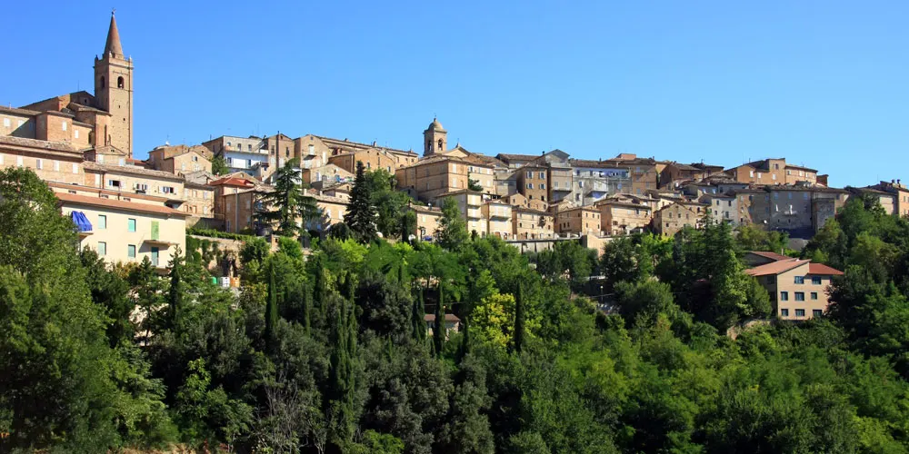 Panorama del borgo medievale di Falerone nelle Marche con campanile e case in pietra tra il verde