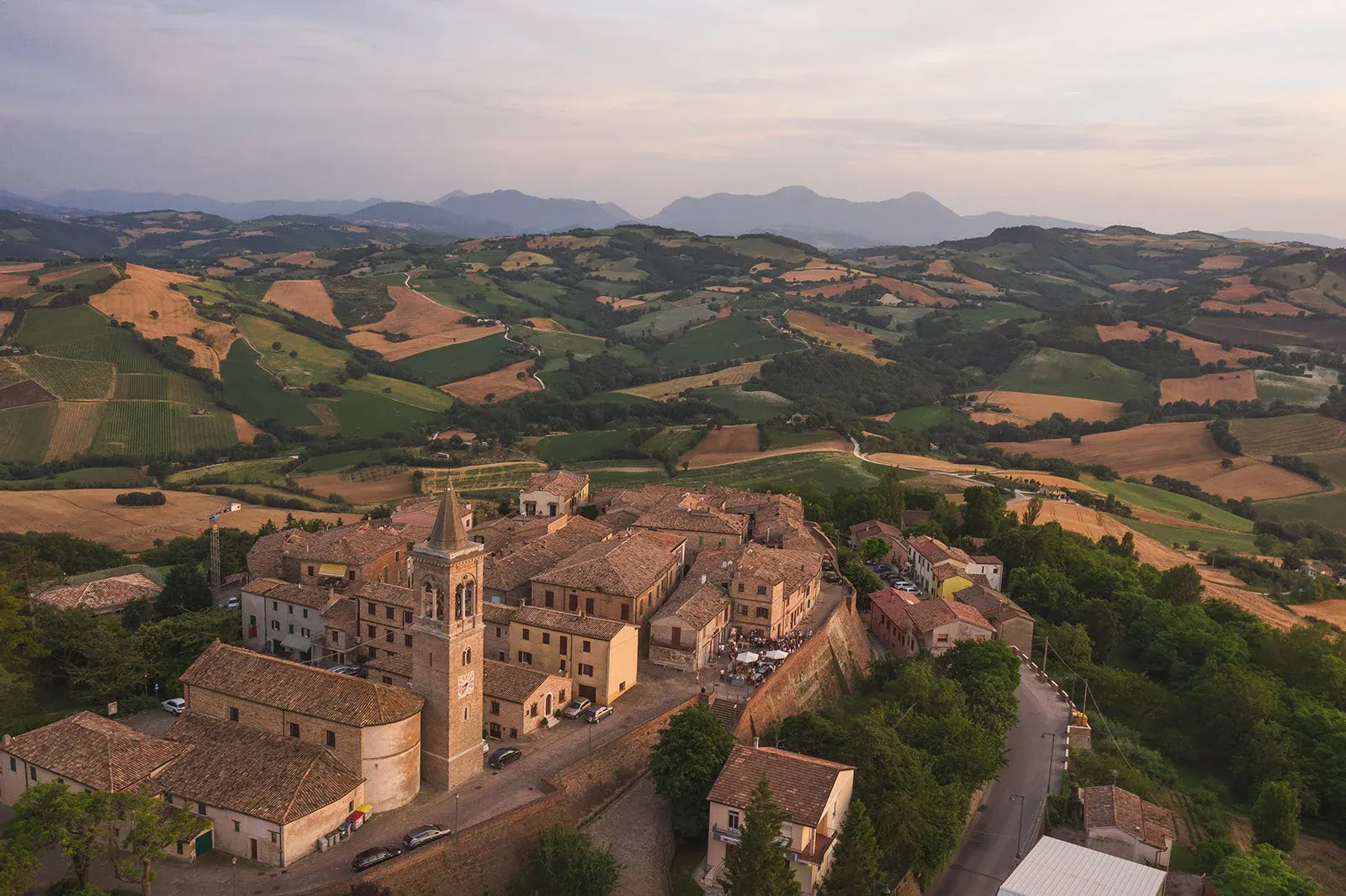 Veduta aerea del borgo medievale di Fratte Rosa circondato da dolci colline marchigiane coltivate