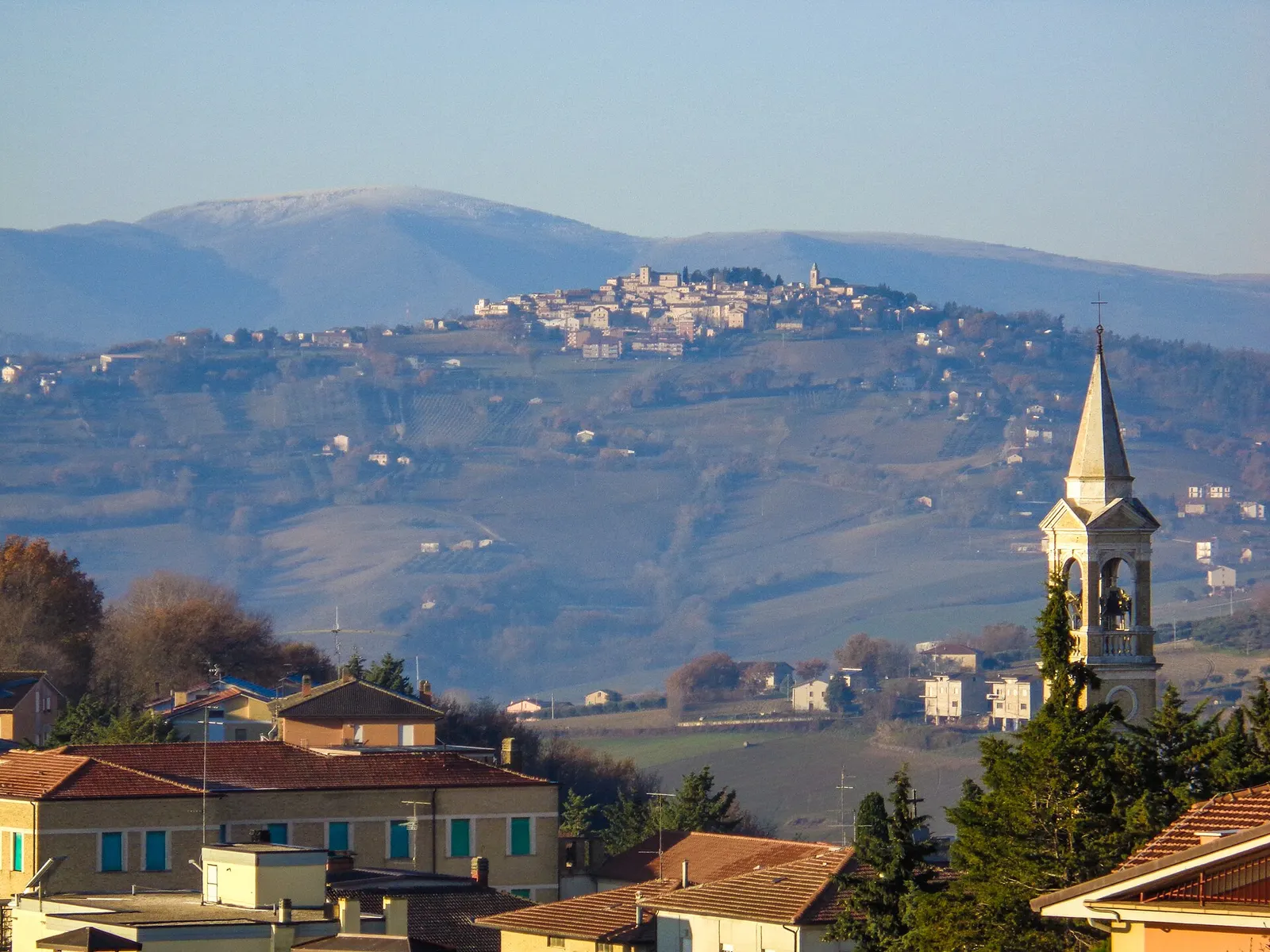 Panorama di Loro Piceno con campanile e borgo medievale sulle colline marchigiane dei Monti Sibillini