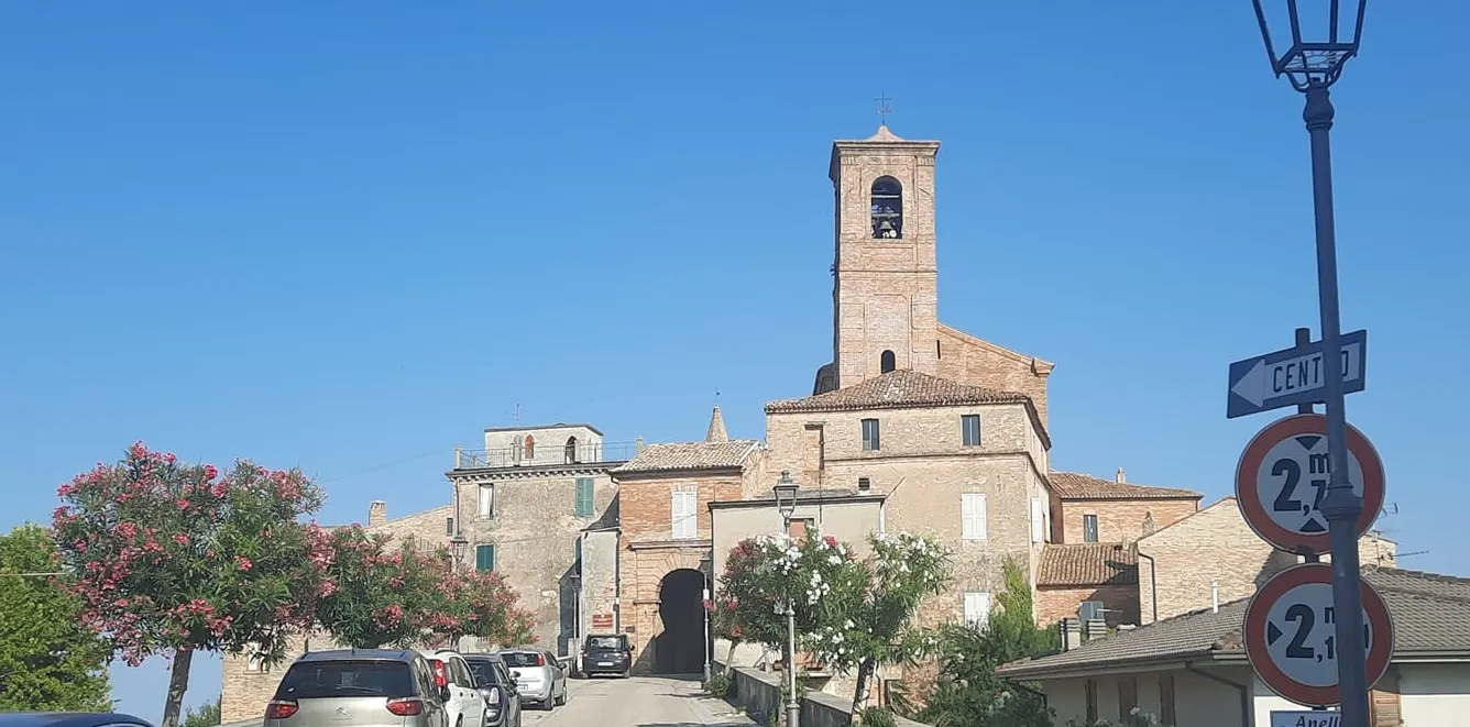 Centro storico di Massignano con campanile e case in pietra sotto il cielo azzurro delle Marche