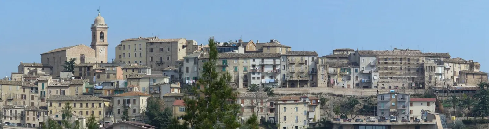 Panorama del centro storico di Monsampolo del Tronto con campanile e case in pietra sotto cielo azzurro