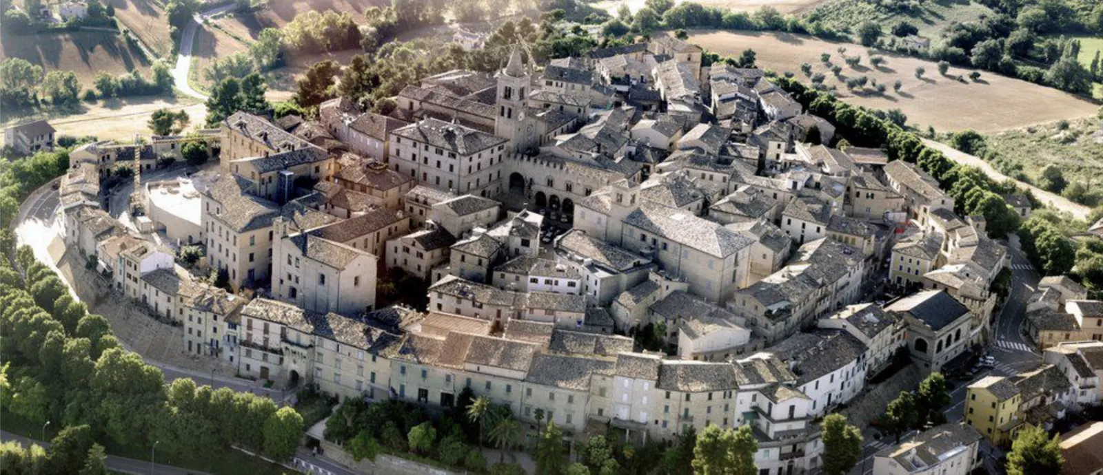 Veduta aerea di borgo medievale murato circondato da colline coltivate nel territorio maceratese delle Marche