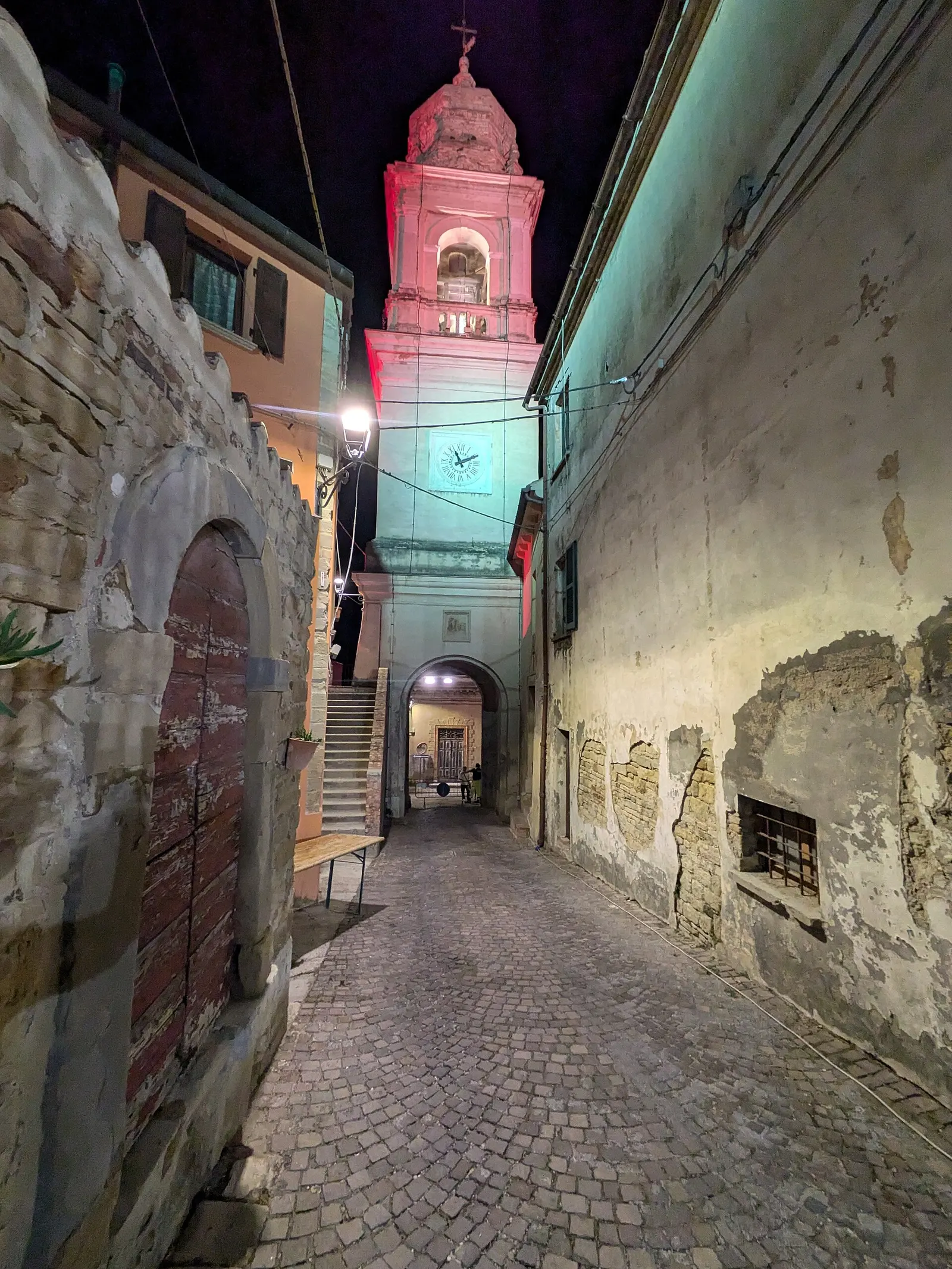 Vicolo storico del centro di Sant'Ippolito con campanile illuminato e case antiche nelle Marche
