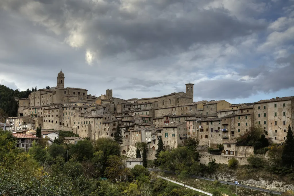 Veduta del borgo medievale di Serra San Quirico adagiato sulle colline marchigiane sotto un cielo nuvoloso