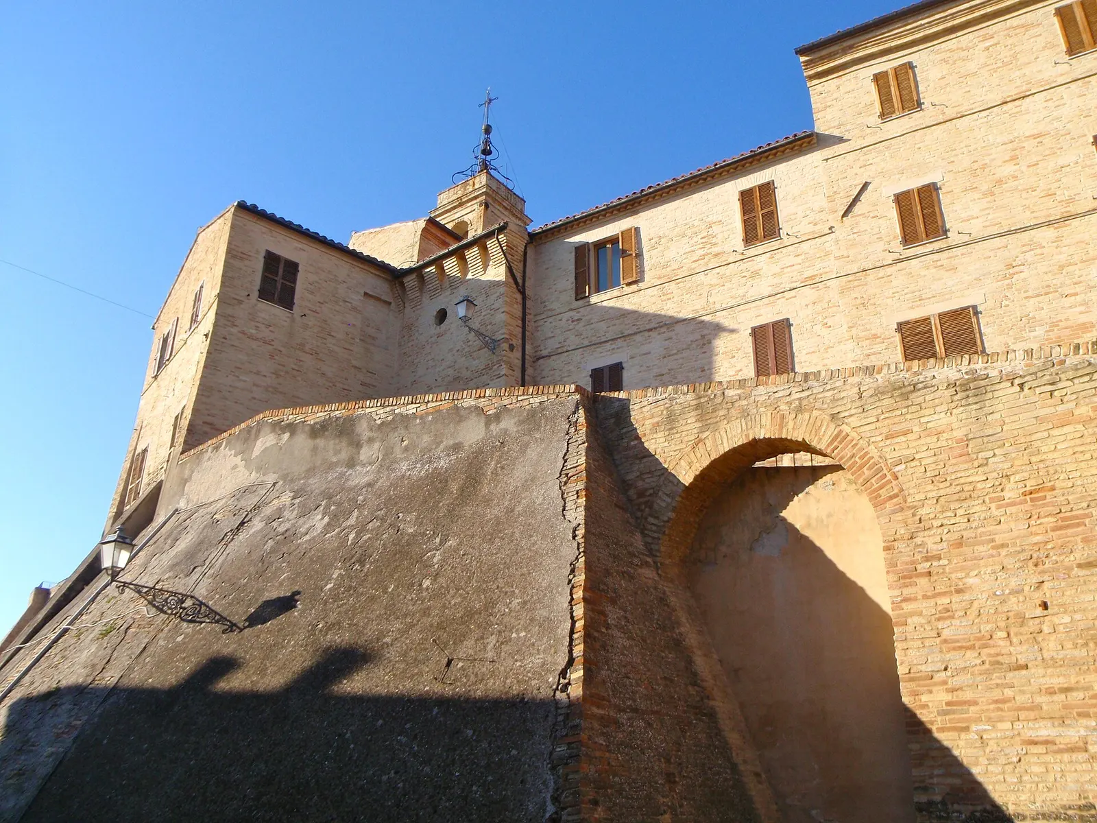 Centro storico di Torre San Patrizio con edifici in mattoni e campanile sotto cielo azzurro nelle Marche