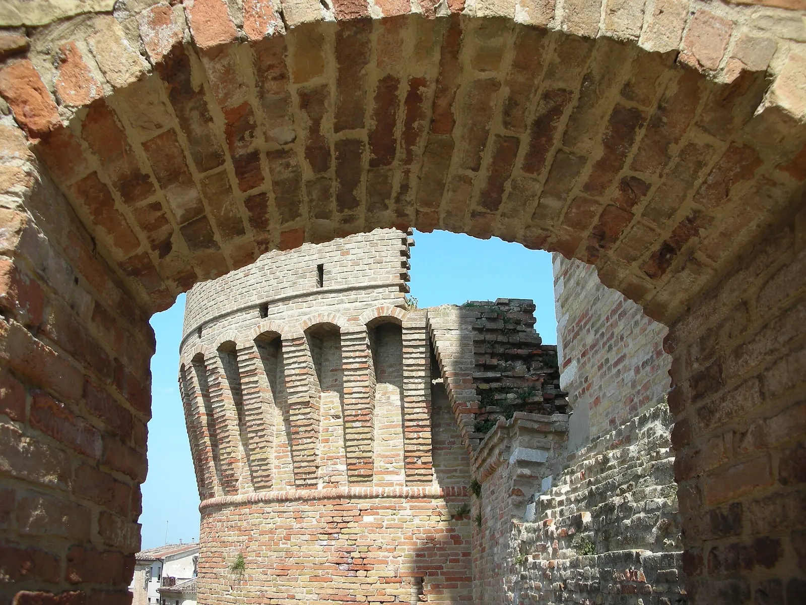 Torre medievale in mattoni vista attraverso un arco della Rocca di Urbisaglia nelle Marche
