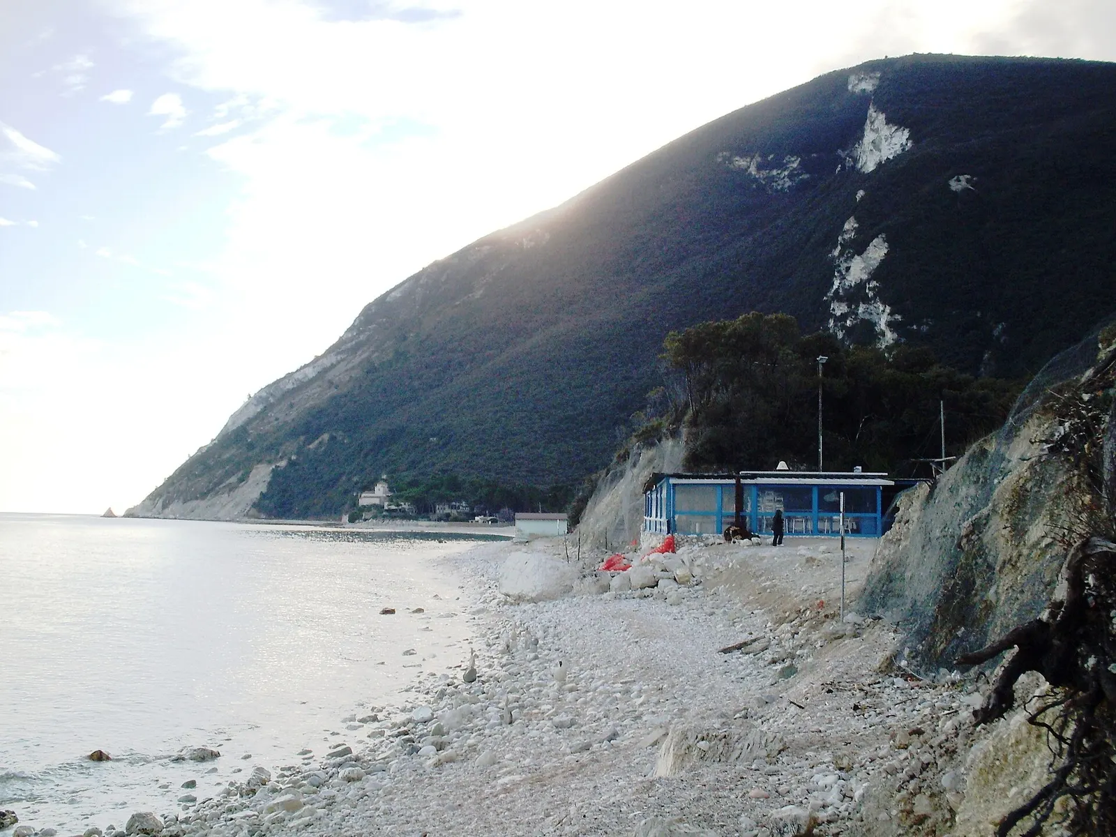 Spiaggia di ciottoli bianchi a Portonovo con stabilimento balneare e Monte Conero sullo sfondo