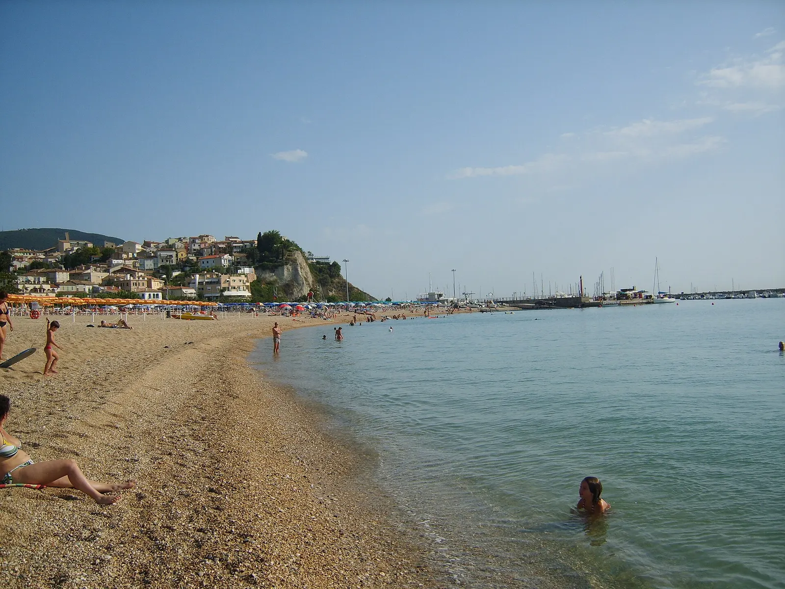 Spiaggia del Frate a Numana con bagnanti mare calmo e promontorio del Conero sullo sfondo