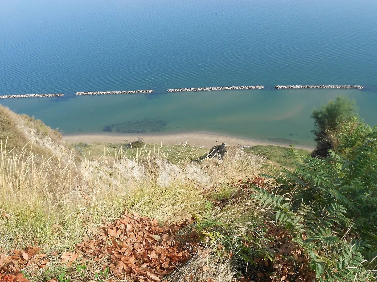 Vista dall'alto della spiaggia di Fiorenzuola di Focara con mare Adriatico e scogliere frangiflutti a Pesaro