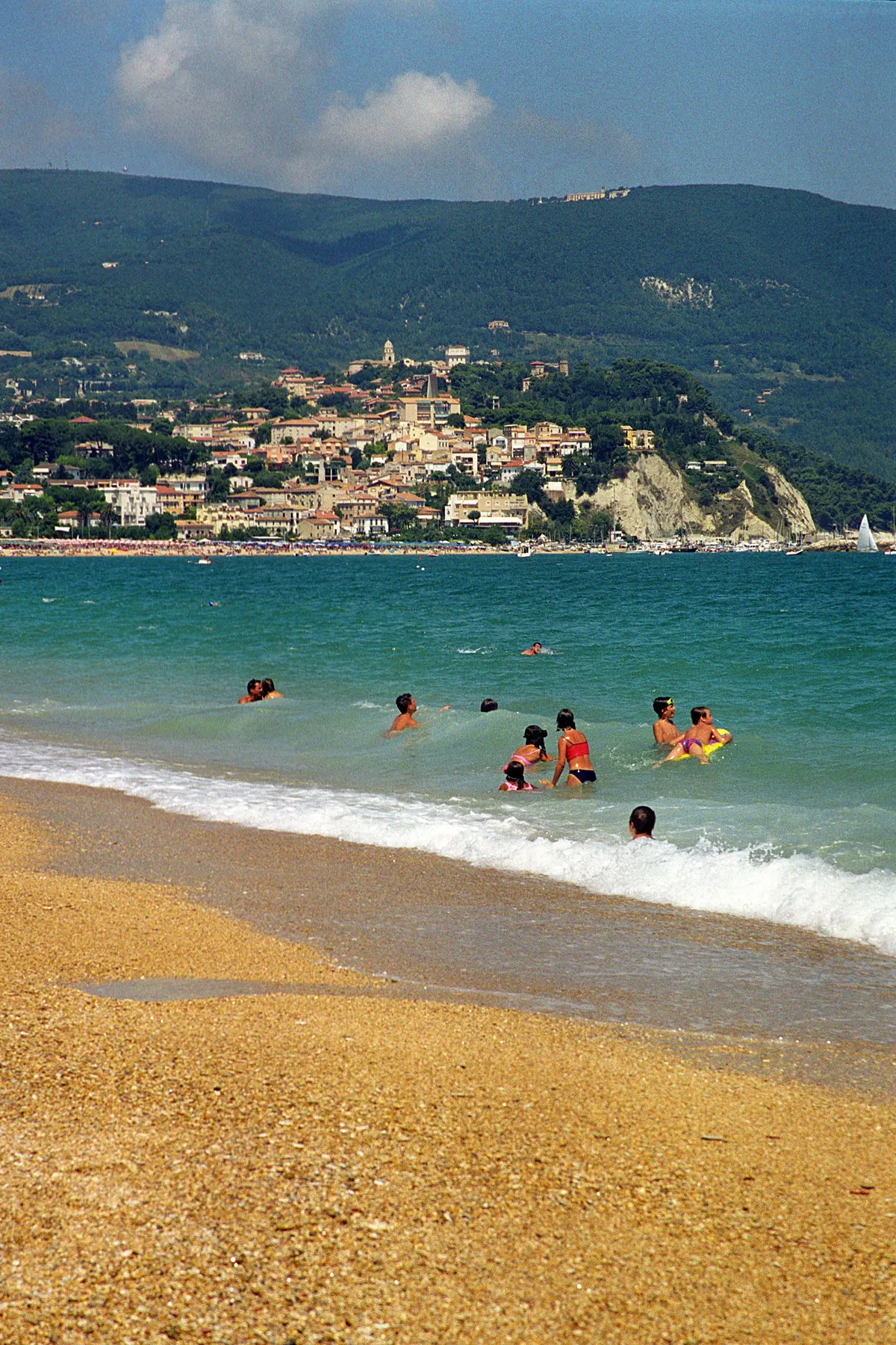 Bagnanti in acqua sulla spiaggia di Marcelli con vista su Numana e Monte Conero sullo sfondo