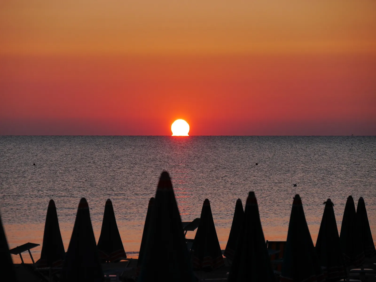 Tramonto sul mare Adriatico con ombrelloni chiusi sulla Spiaggia di Velluto a Senigallia