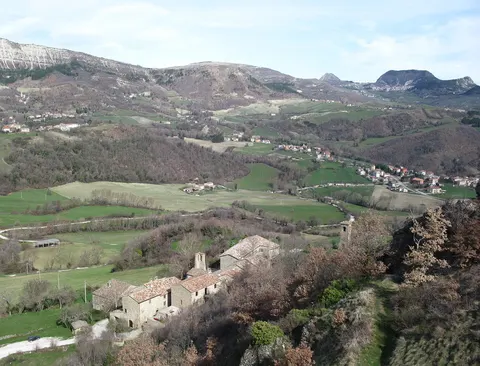 Borgo di Pietrarubbia con case in pietra e colline verdi del Montefeltro marchigiano sullo sfondo