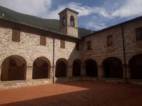 Chiostro in pietra con archi e campanile nel centro storico di Pioraco sulle colline marchigiane
